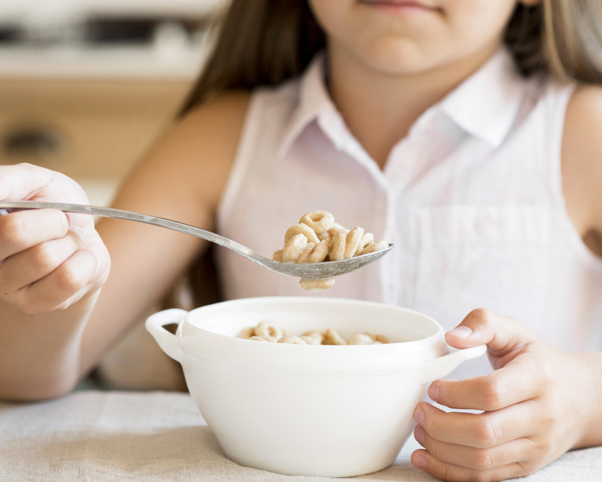 Front view young girl eating cereals breakfast